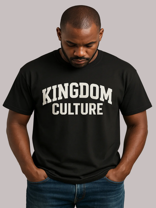 A man wearing a black short-sleeve t-shirt with 'KINGDOM CULTURE' printed in white arched letters across the chest, paired with blue jeans, against a plain beige background.